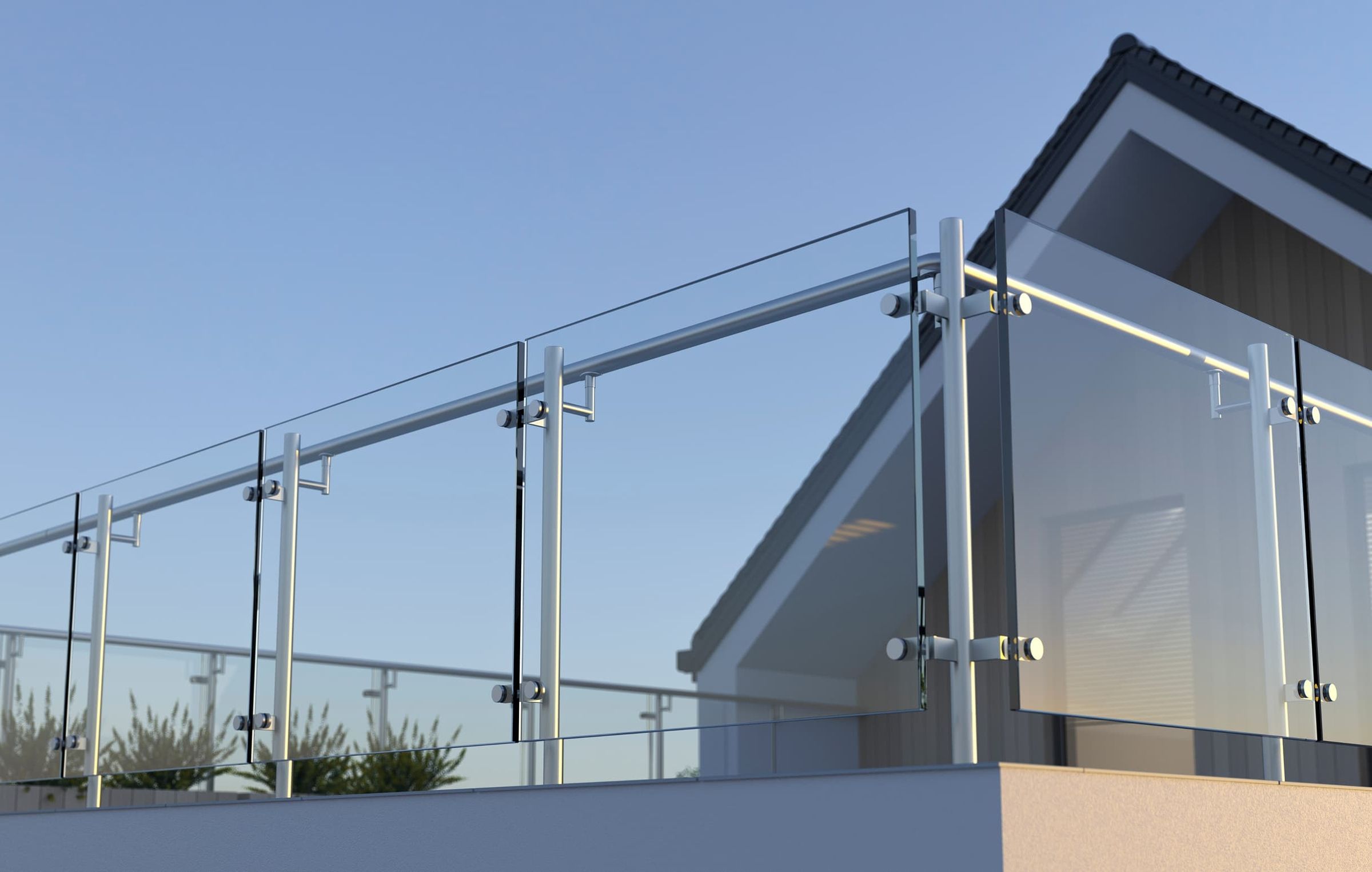 Modern glass railing system with stainless steel posts and handrails on an outdoor balcony against a clear blue sky.